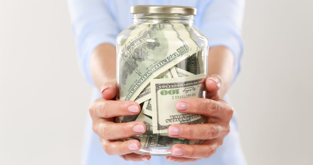 Cropped photo of womans hands holding glass jar with dollar bills, isolated on white background